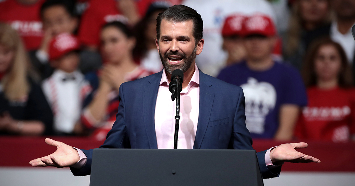 Donald Trump Jr. with hands outstretched at a rally