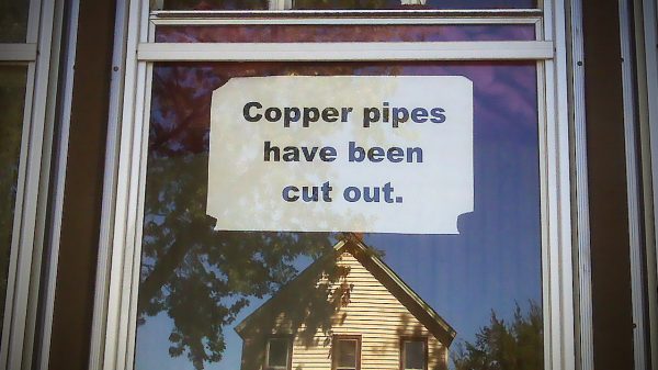Sign that reads "Copper pipes have been cut out" on empty home