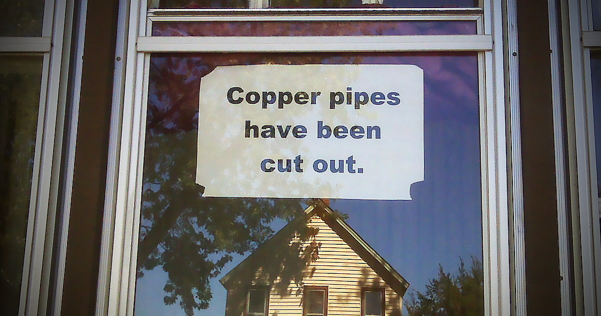 Sign that reads "Copper pipes have been cut out" on empty home
