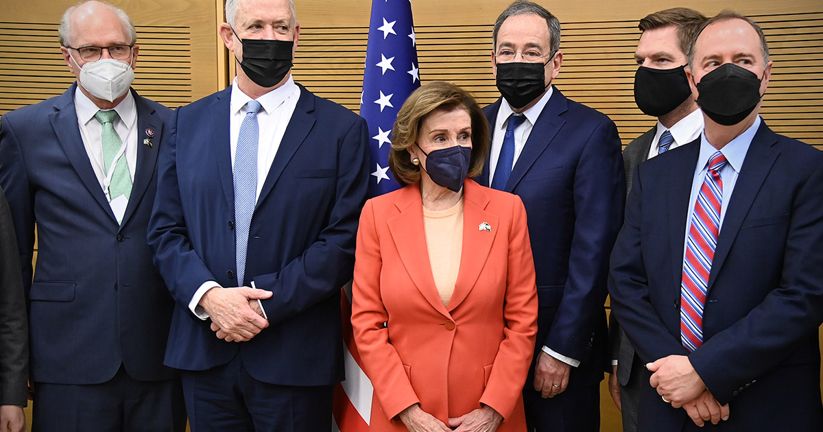Pelosi surrounded by men in suits all wearing face masks