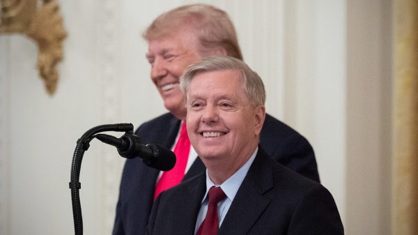 Lindsey Graham standing in front of Donald Trump