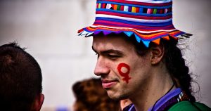 Male feminist with a female gender symbol painted on his cheek at a feminist protest 