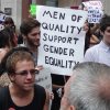 Male feminists protesting with a sign that reads "Men of quality support gender equality"