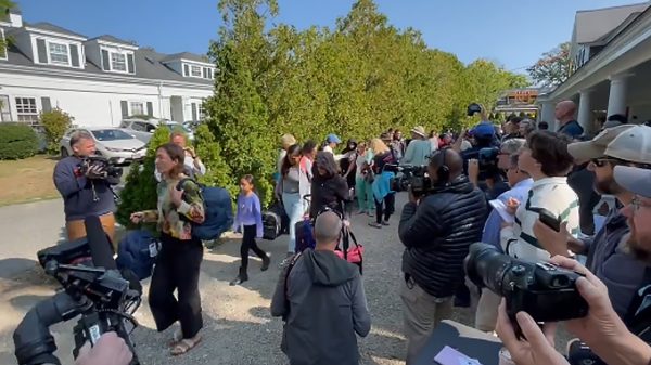 Video still from Martha's Vineyard showing illegal immigrants enter a bus surrounded by a crowd of media