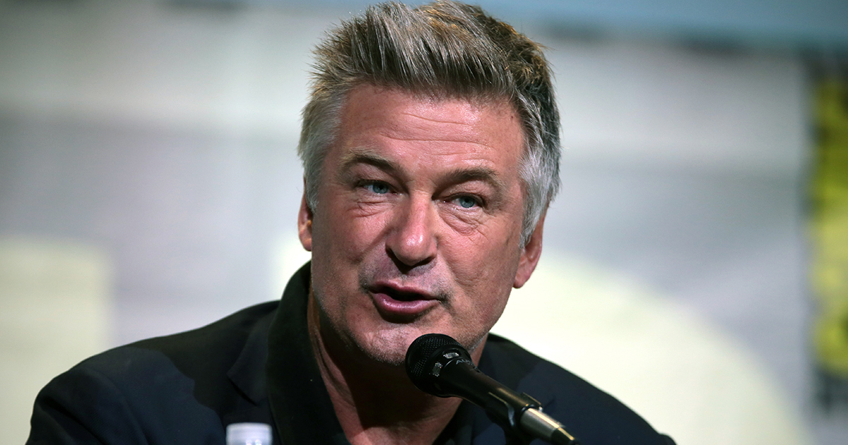 Alec Baldwin with a microphone on stage