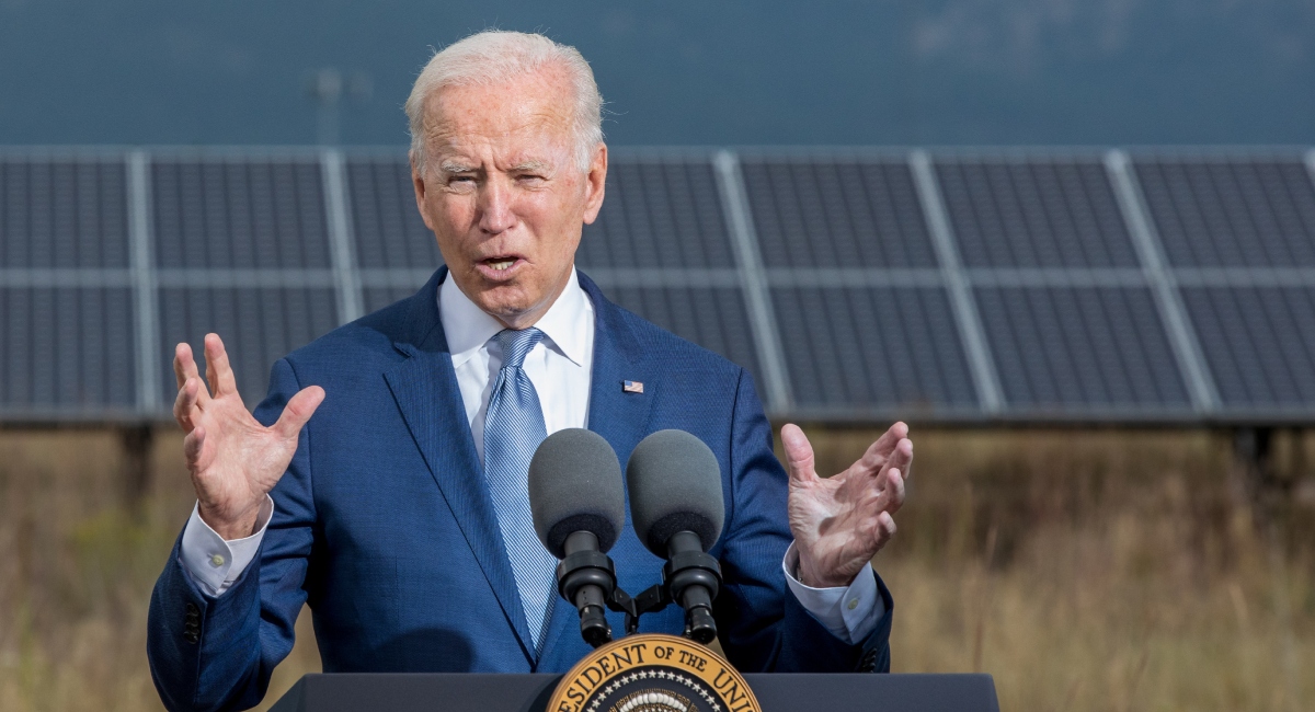 Joe Biden standing in front of an array of solar panels