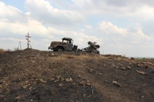 A burned out truck at the top of a desolate hill