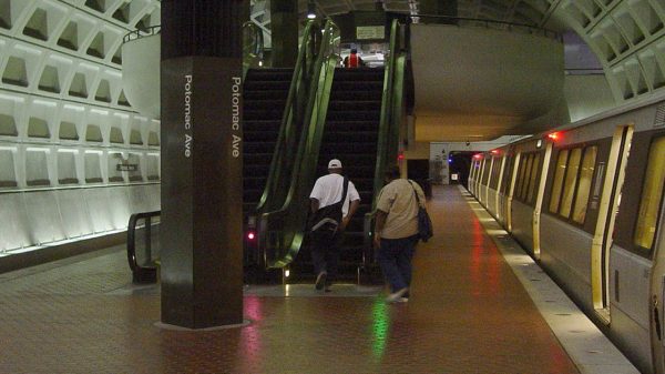 A DC metro stop with two men going up an escalator