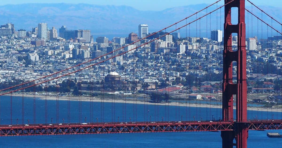 A view of the San Francisco bridge with the bay in the foreground and city in the background