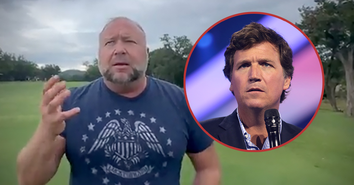 Alex Jones outside with a photo of Tucker Carlson