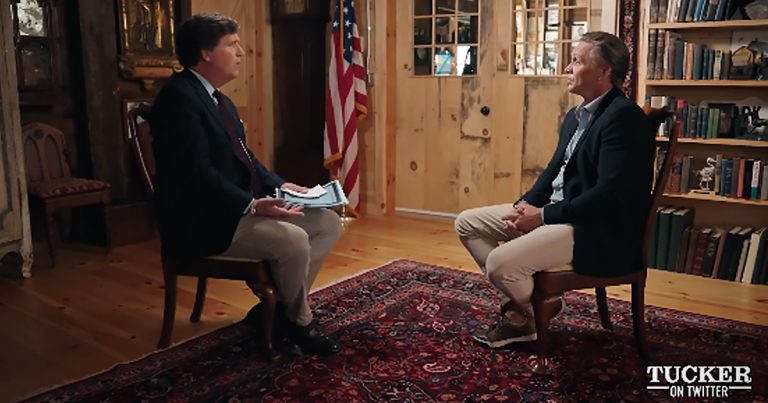 Tucker Carlson sits in a chair next to Devon Archer