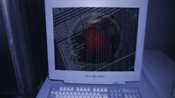 An old CRT computer monitor with code and an ominous red light